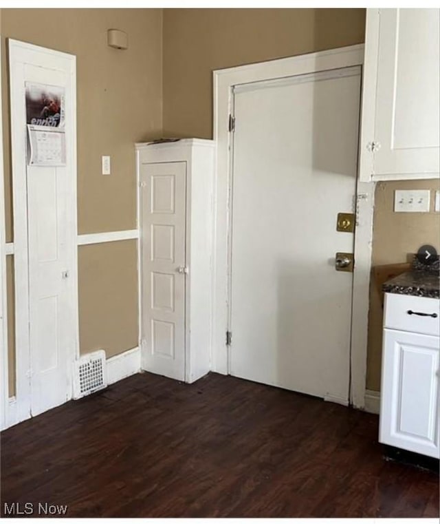 interior space with dark hardwood / wood-style flooring and white cabinetry