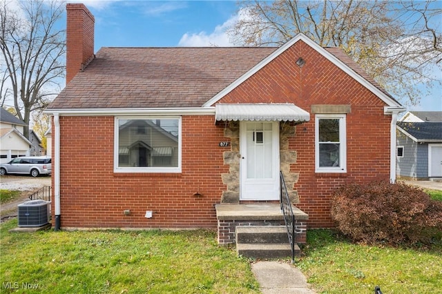 bungalow-style home with cooling unit and a front yard