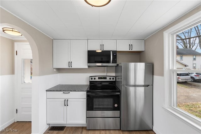 kitchen with light hardwood / wood-style floors, white cabinetry, stainless steel appliances, and a wealth of natural light