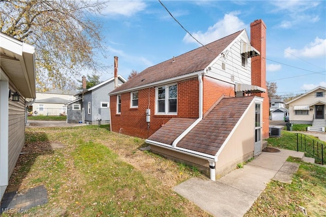 rear view of property with a lawn and cooling unit