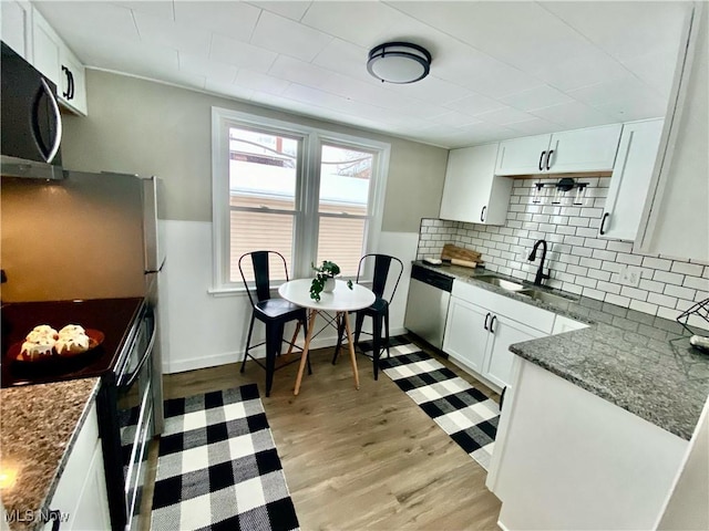 kitchen with white cabinets, sink, tasteful backsplash, light hardwood / wood-style floors, and stainless steel appliances