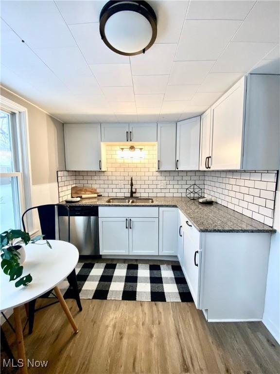 kitchen featuring dark hardwood / wood-style flooring, white cabinetry, sink, and stainless steel dishwasher