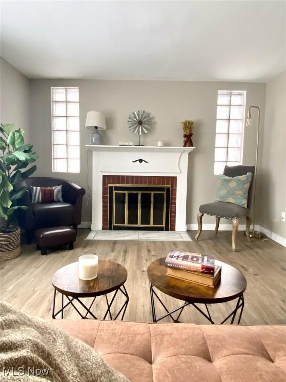 living room with hardwood / wood-style flooring, plenty of natural light, and a brick fireplace