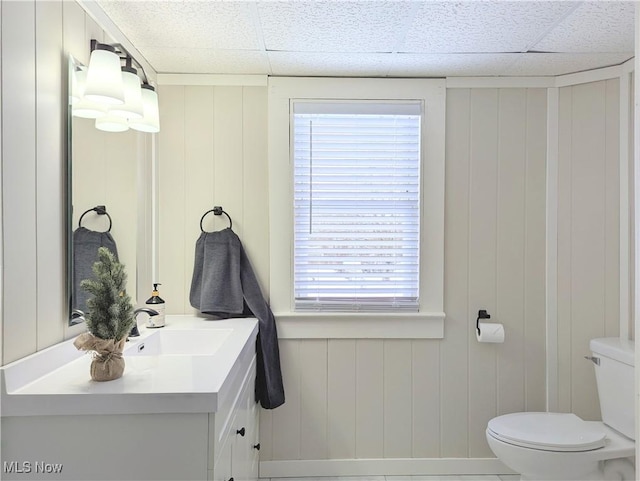 bathroom featuring a paneled ceiling, vanity, and wooden walls