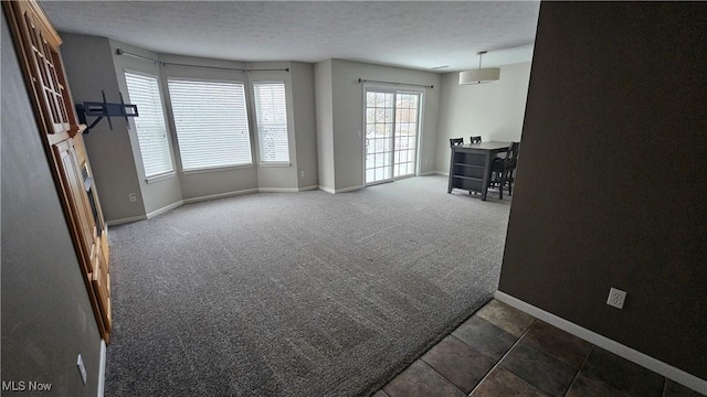 interior space featuring a textured ceiling and dark colored carpet