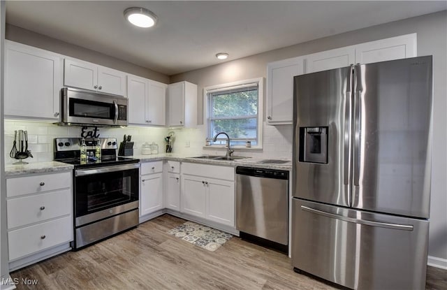 kitchen featuring light stone countertops, tasteful backsplash, stainless steel appliances, sink, and white cabinetry