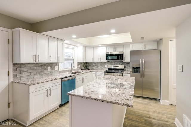 kitchen featuring a center island, stainless steel appliances, white cabinetry, and sink