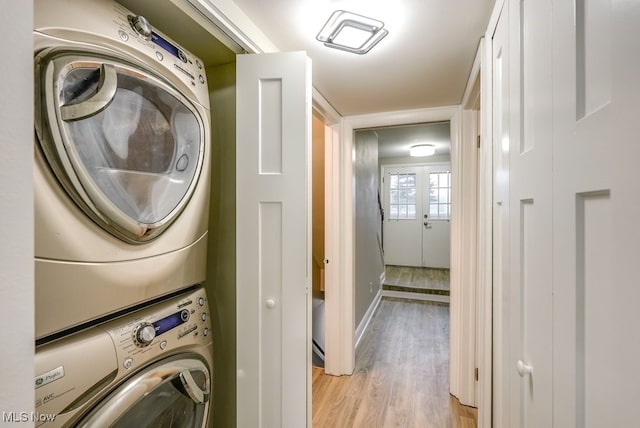 washroom featuring french doors, light wood-type flooring, and stacked washer and dryer