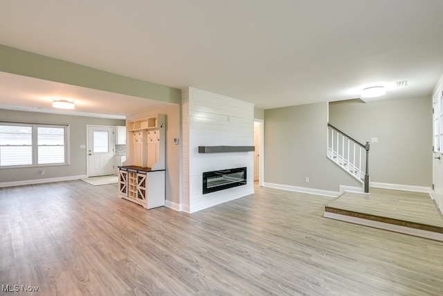 unfurnished living room featuring a large fireplace and light hardwood / wood-style floors