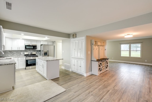 kitchen featuring white cabinets, sink, appliances with stainless steel finishes, tasteful backsplash, and a kitchen island