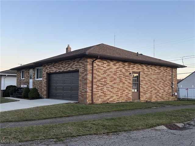 property exterior at dusk featuring a garage and a yard