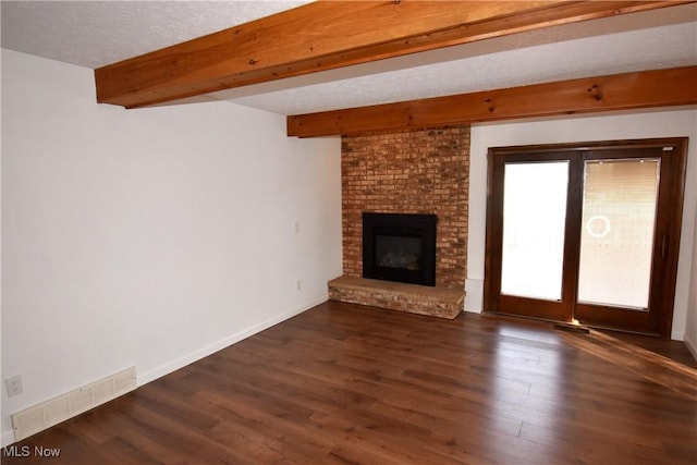 unfurnished living room with beam ceiling, a fireplace, dark wood-type flooring, and a textured ceiling