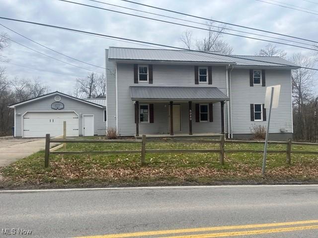 view of front property with a porch, a garage, and an outbuilding