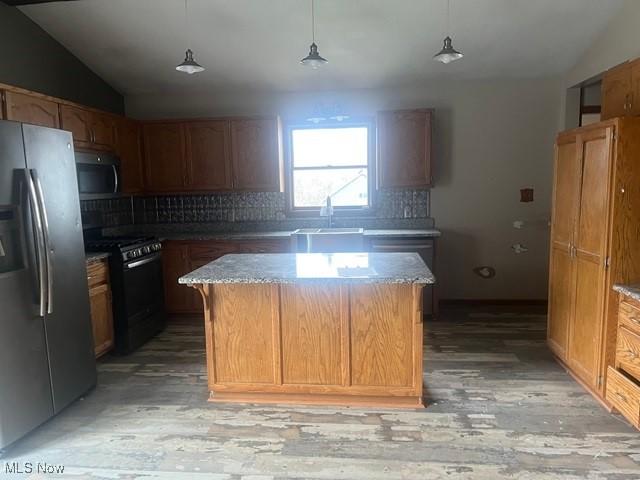 kitchen featuring pendant lighting, a kitchen island, sink, and appliances with stainless steel finishes