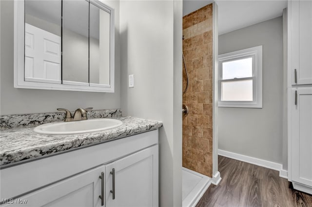 bathroom with hardwood / wood-style flooring, vanity, and tiled shower