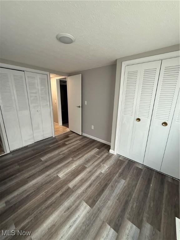 unfurnished bedroom featuring a textured ceiling and dark wood-type flooring