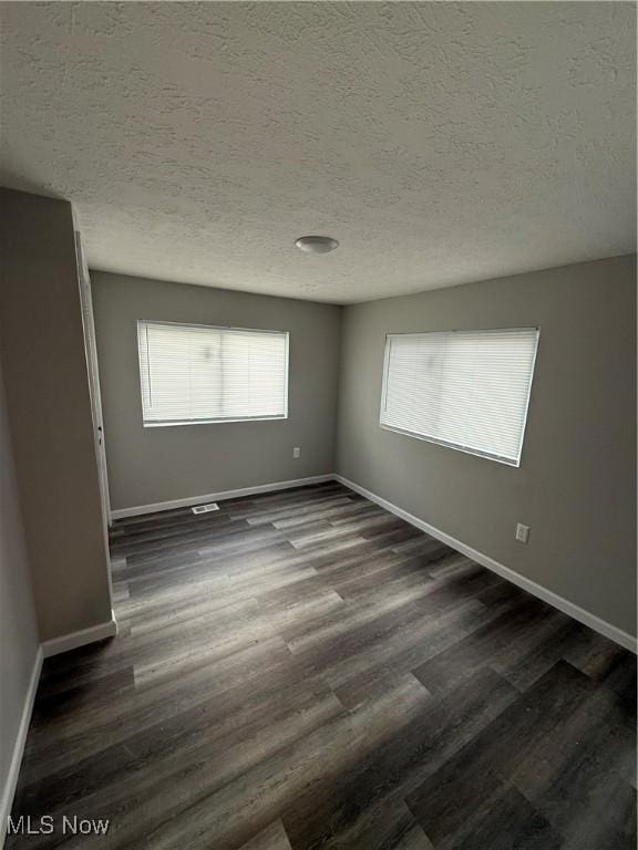 spare room featuring dark hardwood / wood-style flooring and a textured ceiling