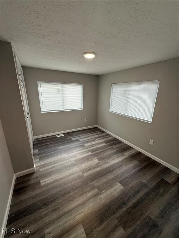 empty room featuring dark hardwood / wood-style flooring and a textured ceiling