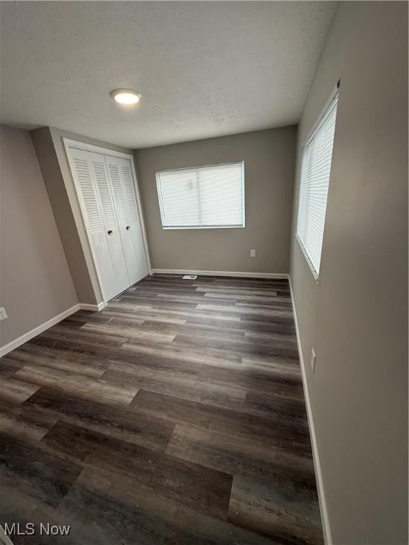 unfurnished bedroom featuring a closet, dark wood-type flooring, and a textured ceiling