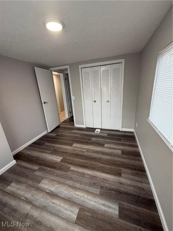 unfurnished bedroom with dark wood-type flooring and a closet