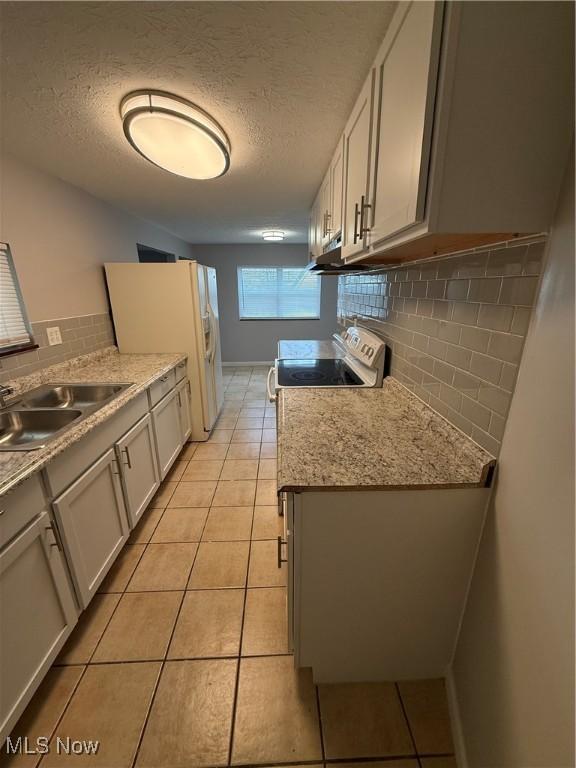 kitchen featuring decorative backsplash, light tile patterned floors, a textured ceiling, and sink