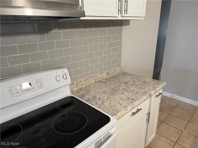 kitchen featuring decorative backsplash, exhaust hood, light tile patterned floors, white electric stove, and white cabinets