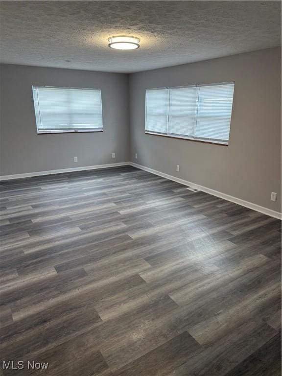 unfurnished room featuring dark hardwood / wood-style flooring and a textured ceiling