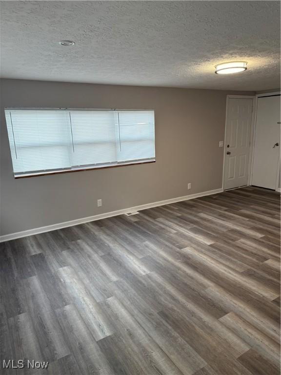 empty room featuring dark hardwood / wood-style flooring and a textured ceiling