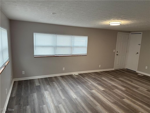 spare room featuring dark hardwood / wood-style floors and a textured ceiling