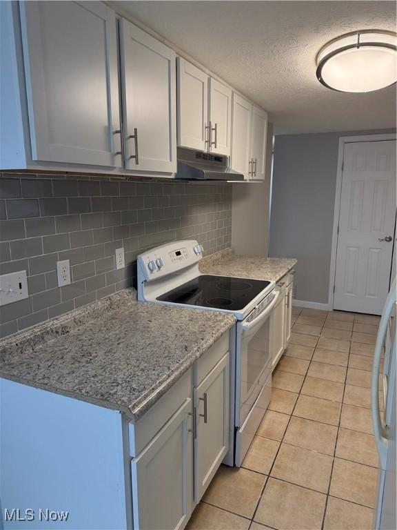 kitchen with light tile patterned floors, electric range, tasteful backsplash, and white cabinetry