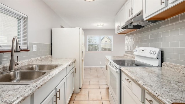 kitchen featuring light tile patterned floors, under cabinet range hood, white appliances, a sink, and white cabinetry