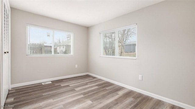 unfurnished room featuring a wealth of natural light, baseboards, and wood finished floors