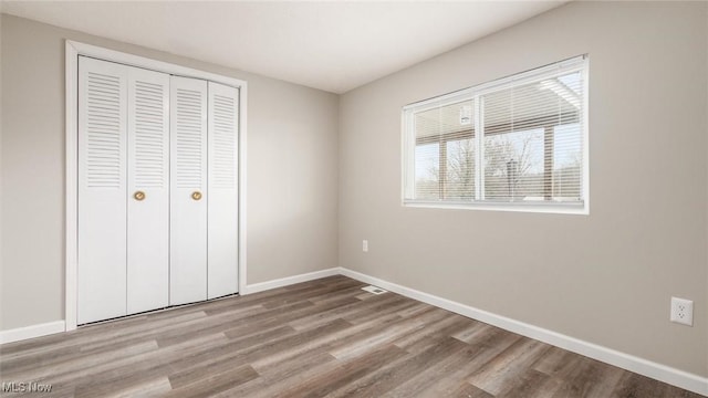 unfurnished bedroom featuring a closet, baseboards, and wood finished floors