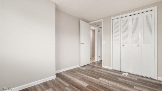 unfurnished bedroom with a closet, baseboards, and wood finished floors