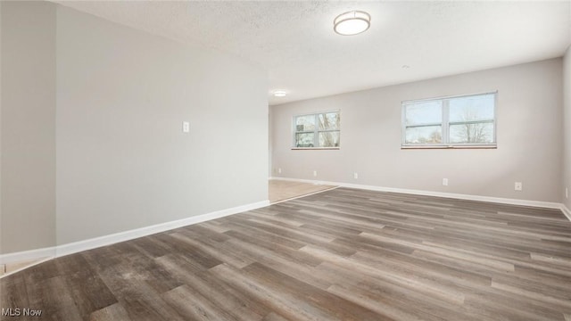 unfurnished room featuring a textured ceiling, wood finished floors, and baseboards