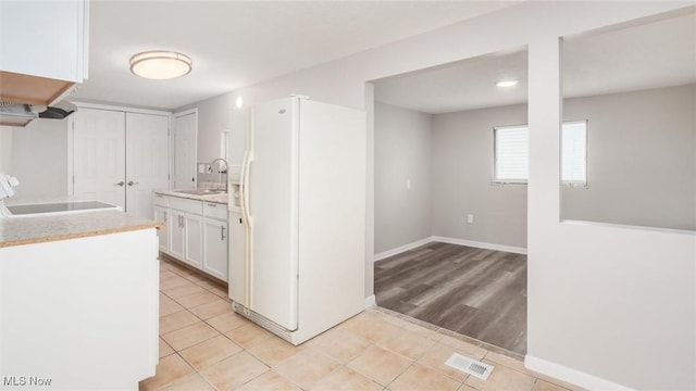 kitchen featuring white fridge with ice dispenser, light tile patterned flooring, a sink, and visible vents