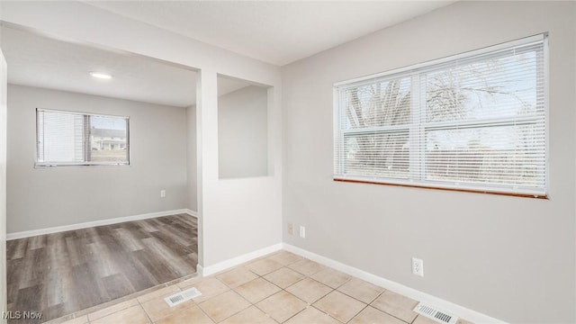 empty room with baseboards, visible vents, and tile patterned floors