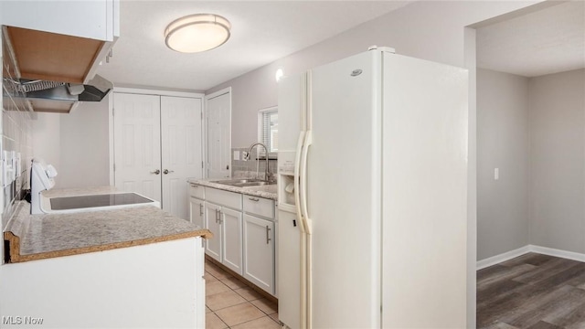 kitchen featuring white cabinets, range, light countertops, white fridge with ice dispenser, and a sink