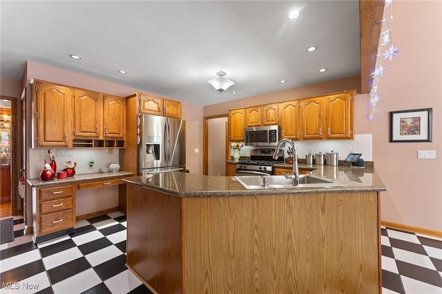 kitchen featuring kitchen peninsula, sink, dark stone countertops, and appliances with stainless steel finishes