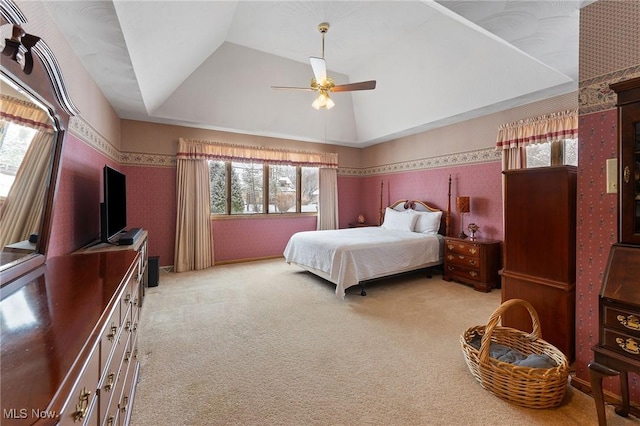 bedroom with a raised ceiling, ceiling fan, and light colored carpet