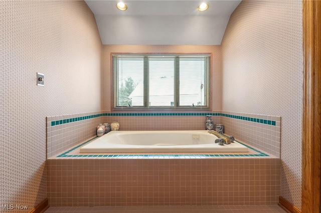 bathroom featuring tile patterned flooring, a relaxing tiled tub, and lofted ceiling