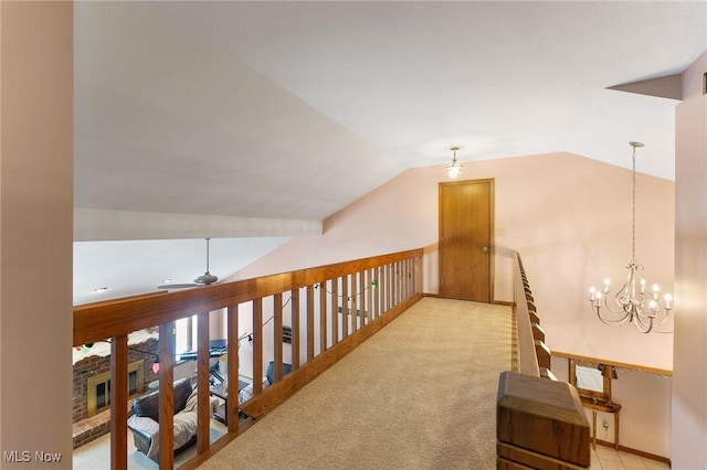 corridor with light carpet, a chandelier, and vaulted ceiling