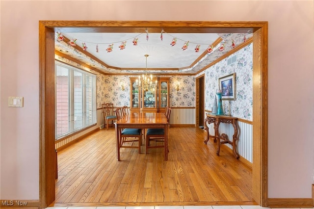 dining room with ornamental molding, wood-type flooring, and an inviting chandelier