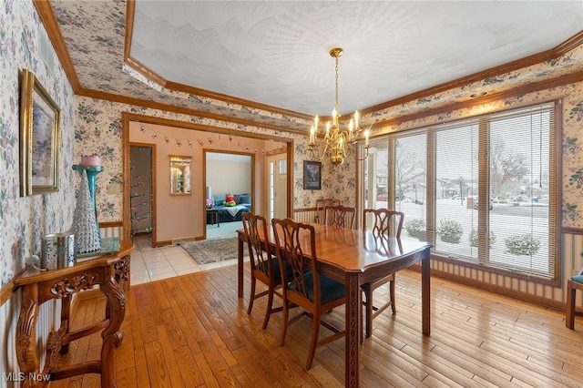 dining area with light hardwood / wood-style floors, an inviting chandelier, and crown molding