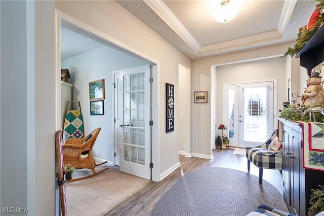 entryway featuring wood-type flooring, a raised ceiling, french doors, and crown molding