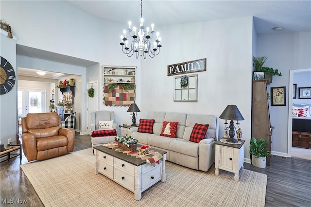 living room featuring wood-type flooring, a towering ceiling, and a chandelier