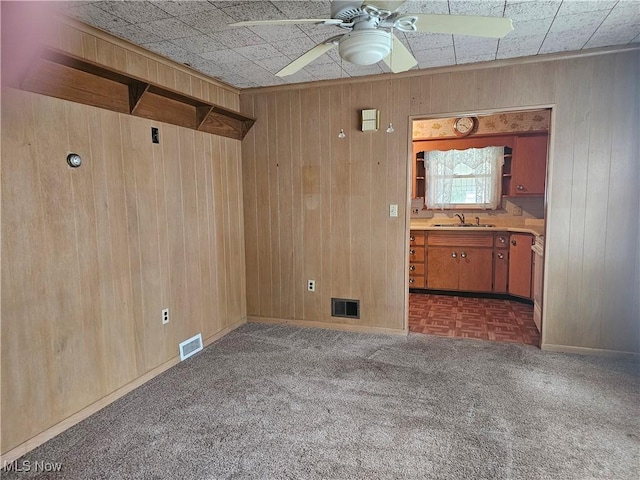 spare room featuring ceiling fan, wood walls, and sink