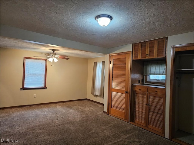 interior space with ceiling fan, carpet, and a textured ceiling