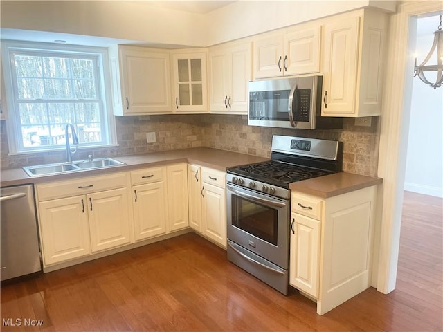 kitchen featuring white cabinetry, sink, wood-type flooring, and appliances with stainless steel finishes