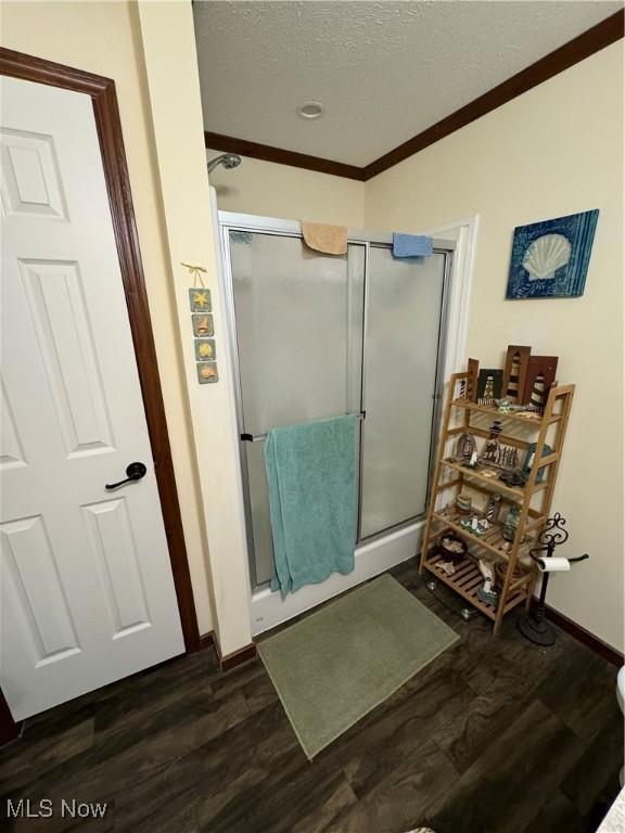 bathroom featuring wood-type flooring, a textured ceiling, walk in shower, and crown molding